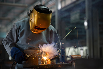 Industrial welder is welding metal part in the factory.