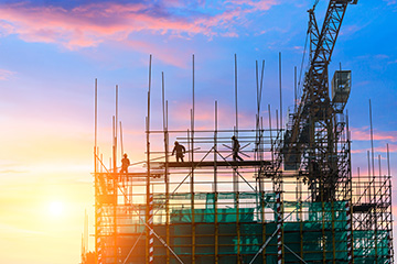 Construction site with crane and workers at sunset